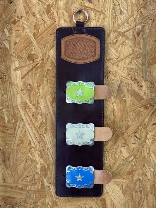 Handmade leather trophy buckle display holding three western buckles.