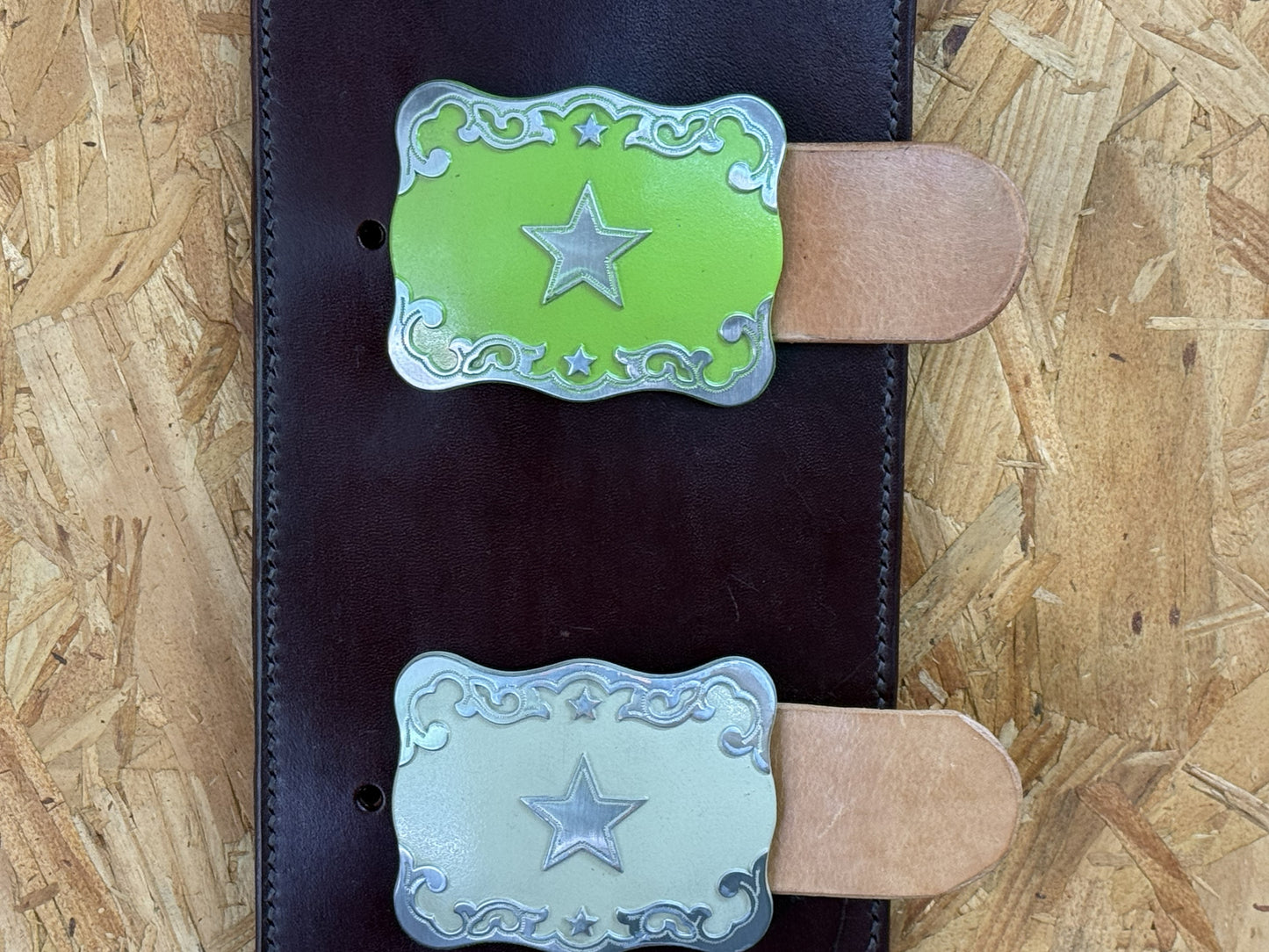 Close-up of interchangeable western trophy buckle holders on leather display.