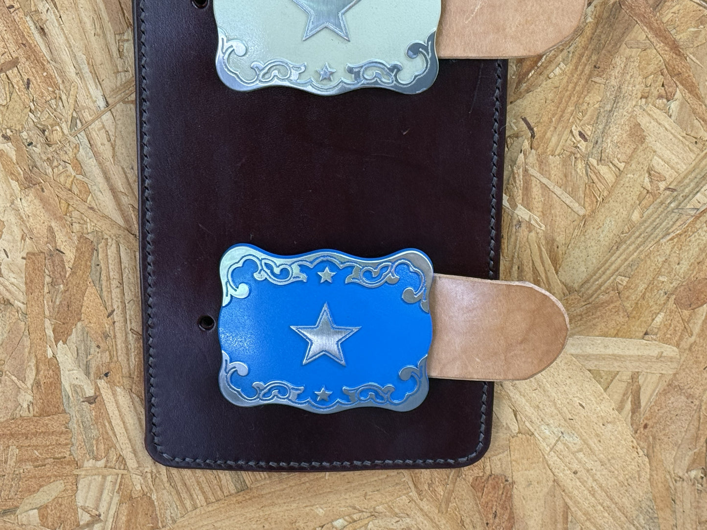 Blue western trophy buckle mounted on handcrafted leather display.