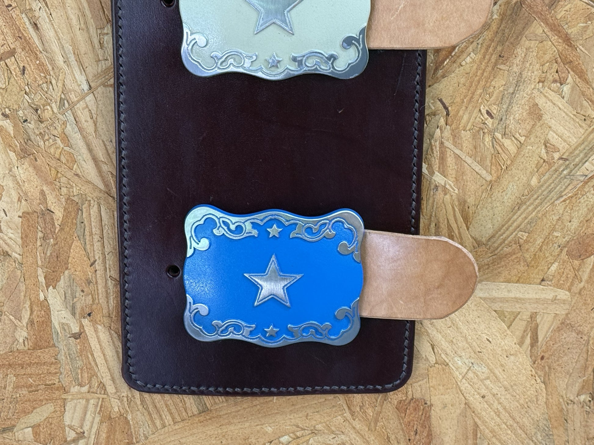 Blue western trophy buckle mounted on handcrafted leather display.